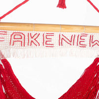 Portable swing red hanging chair with fake news sign  