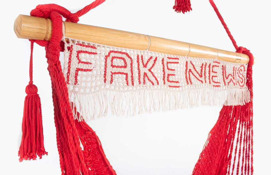 Hanging red rope hammock swing chair with fake news sign